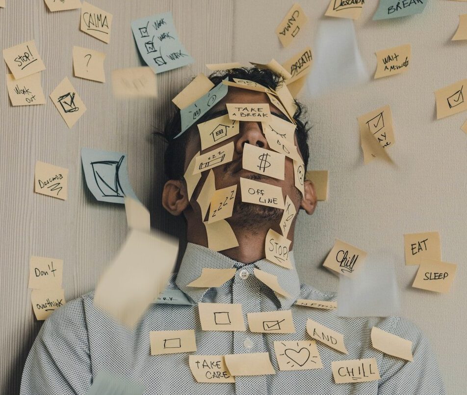 man covered in sticky notes at office desk