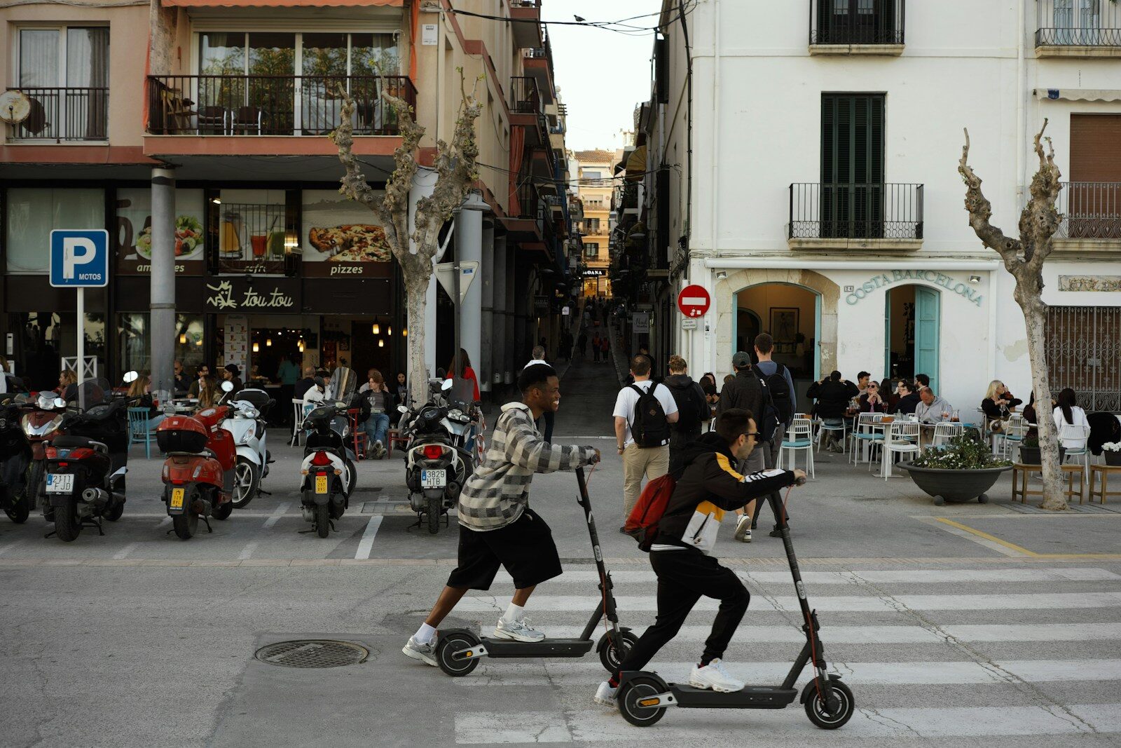 Two young people riding electric scooters on a street