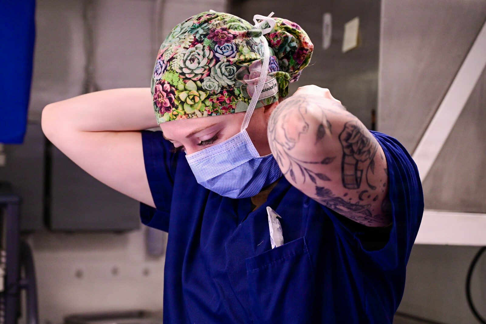 Healthcare professional adjusting a blue surgical mask